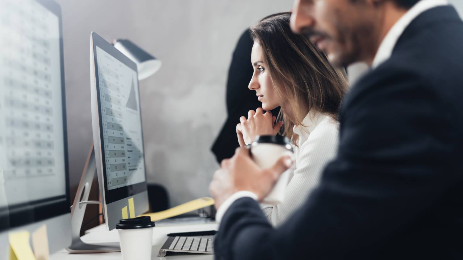 Coworkers study computer screens to understand data classification, governance and compliance